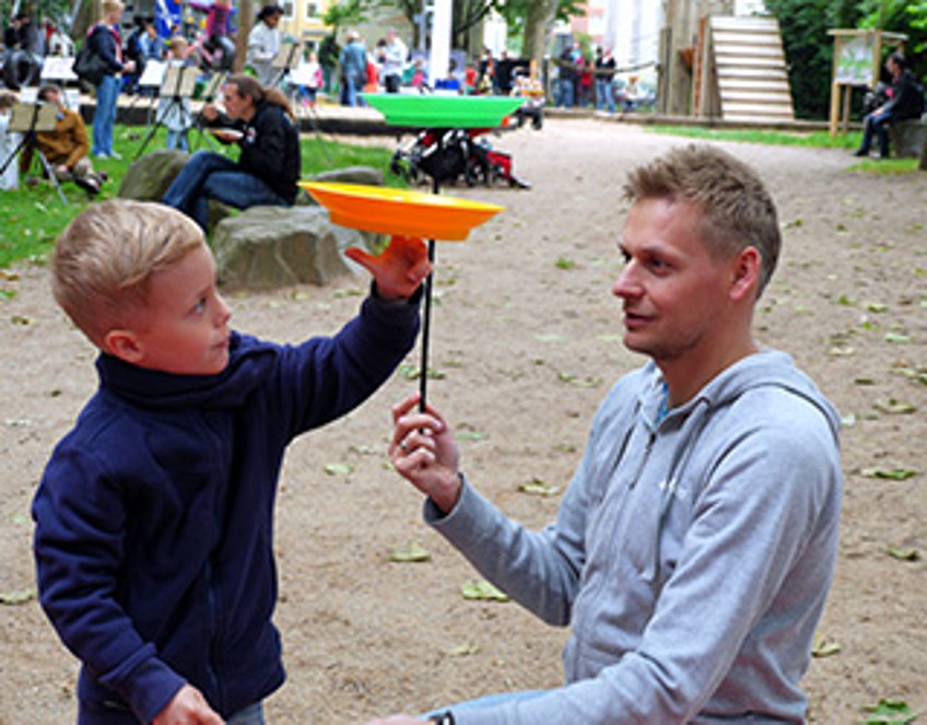 Schlagzeilen - Vater spielt mit seinem Sohn auf Spielplatz