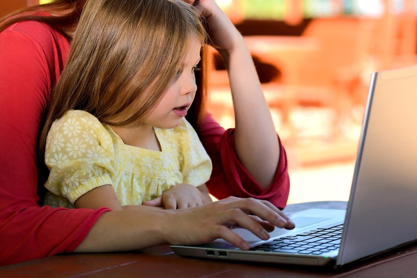 Schlagzeilen - Mutter arbeit mit Kind auf dem Schoß am Laptop