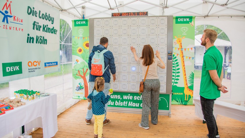 Eine Familie spielt ein Spiel im DEVK-Zelt beim Benefizrenntag zugunsten des Kinderschutzbunds Köln