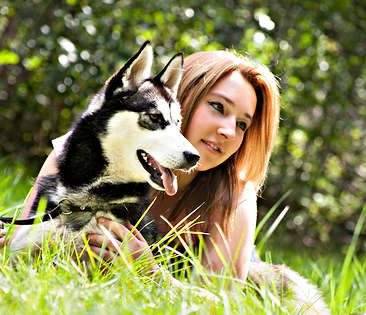 Hapftpflicht-Tierhalter - Frau liegt mit Hund auf einer Wiese 