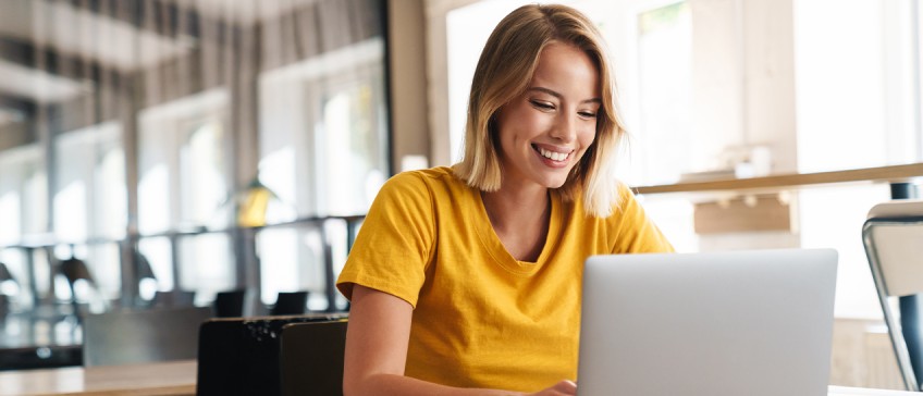 Mediathek - Frau guckt lächelnd auf Laptop