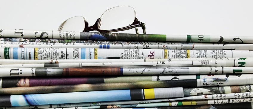 Newsfeed - Lesebrille liegt auf Zeitungsstapel