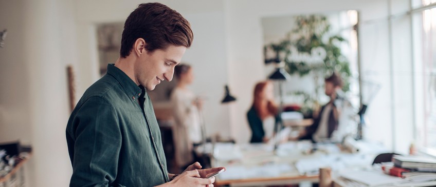 Handyverbot am Arbeitsplatz - Mann mit Smartphone im Büro