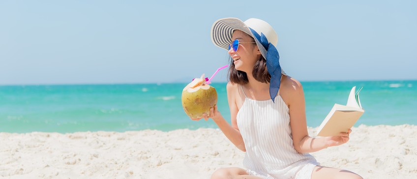 Resturlaub - Frau am Strand mit Buch und Kokosnuss 