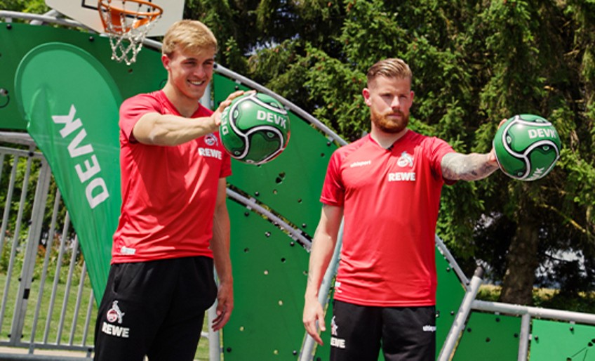 DEVK-Waterballoon-Challenge: Timo Hübers und Timo Horn halten DEVK-Fußbälle in den Händen