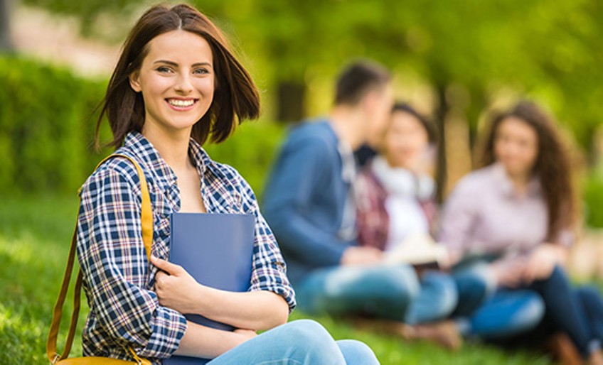 Studenten-Haftpflichtversicherung - Studentin sitzt im Park