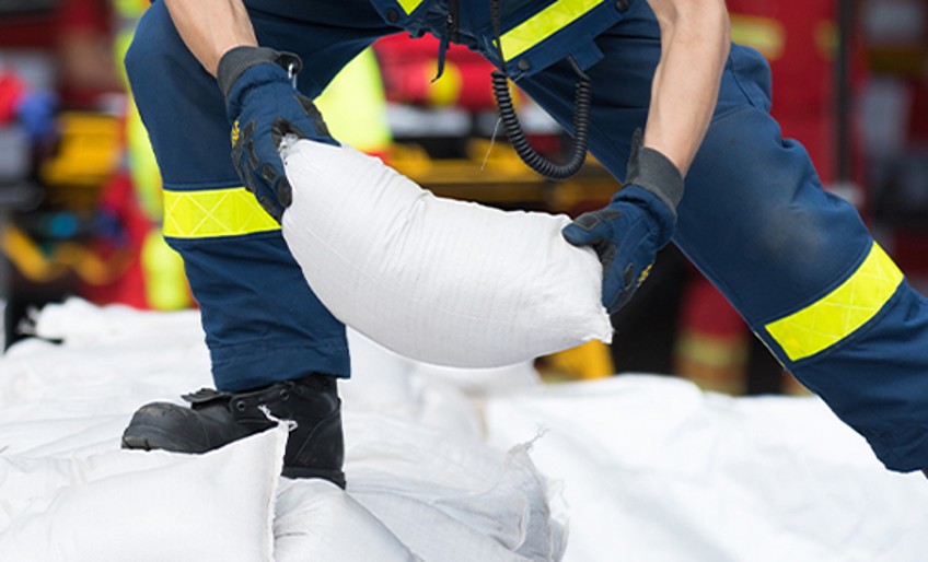 Naturgefahrenversicherung - Feuerwehrmann stapelt Sandsäcke