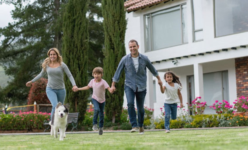 Wohngebäudeversicherung – Familie im Garten vor Hausfassade