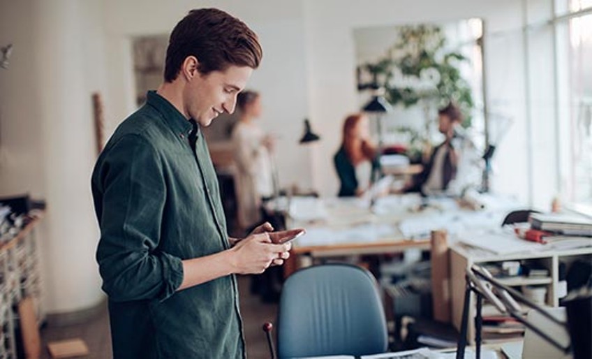 Handyverbot am Arbeitsplatz - Mann mit Smartphone im Büro