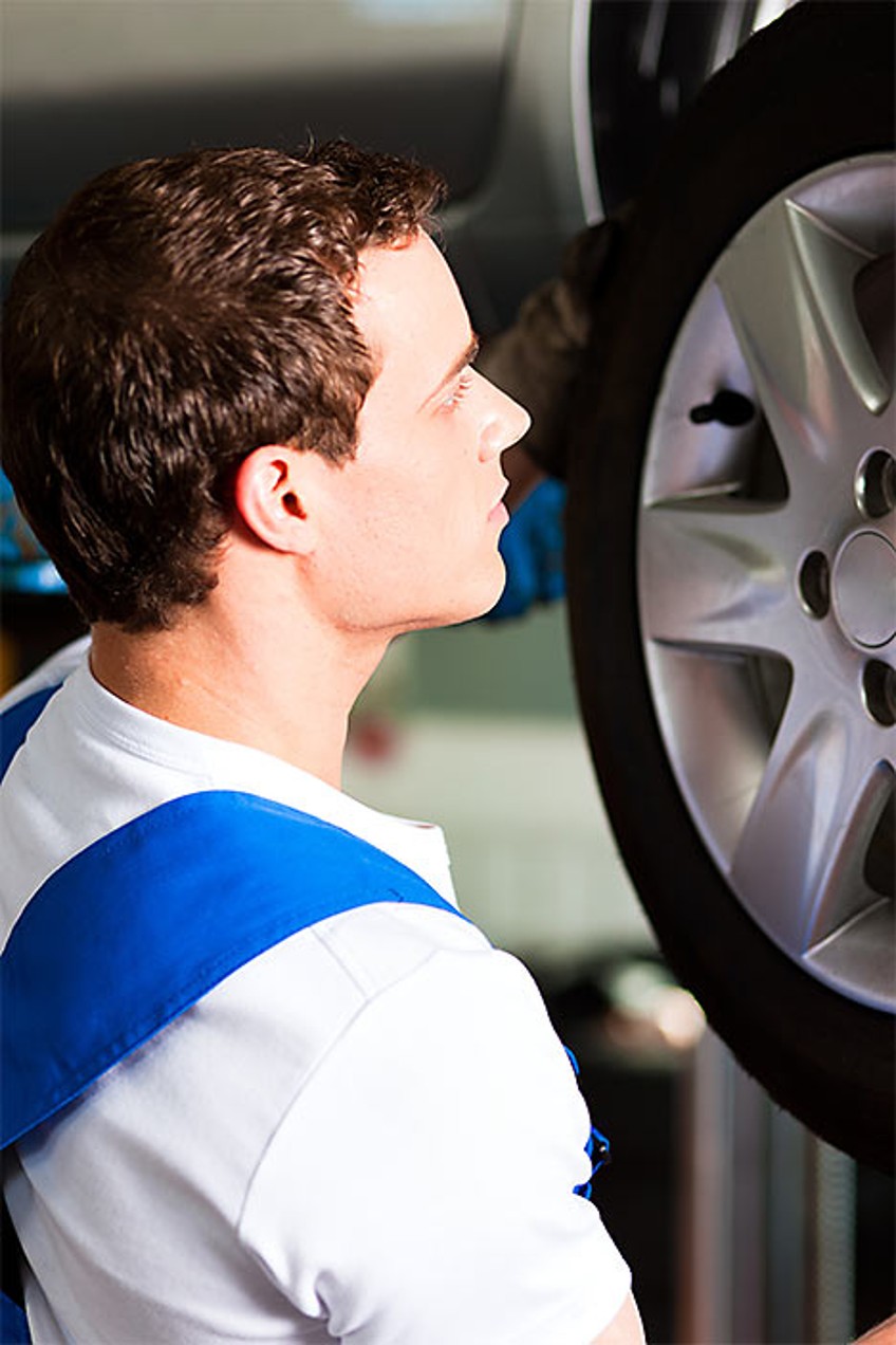 Pressemitteilung Reifenwechsel - Mechaniker steht vor Autoreifen 