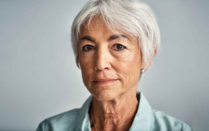 Pressemitteilung Altersarmut - ältere Frau vor grauem Hintergrund