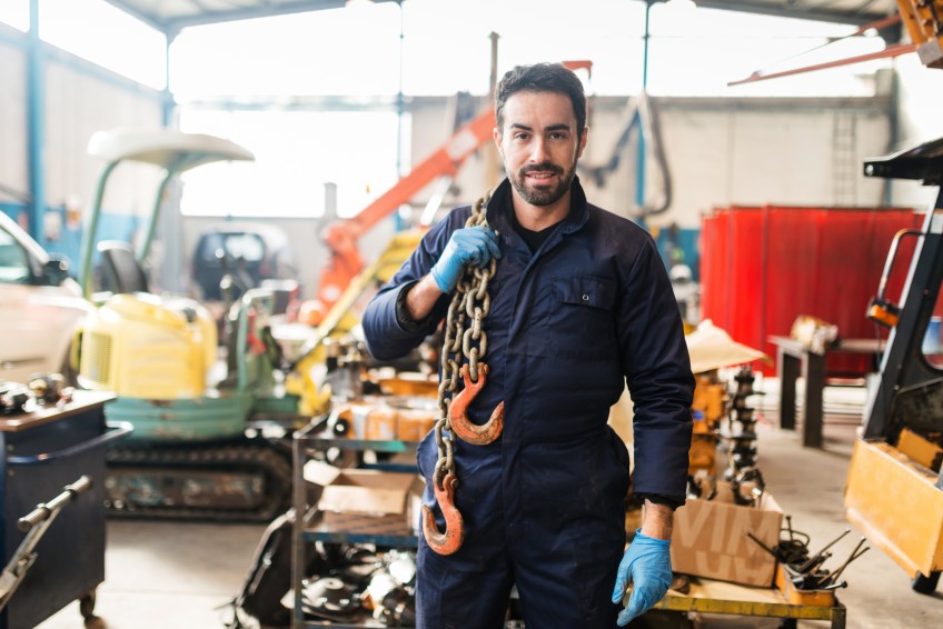 Pressemitteilung Grundfähigkeit - Arbeiter trägt schwere Zurrkette auf der Schulter