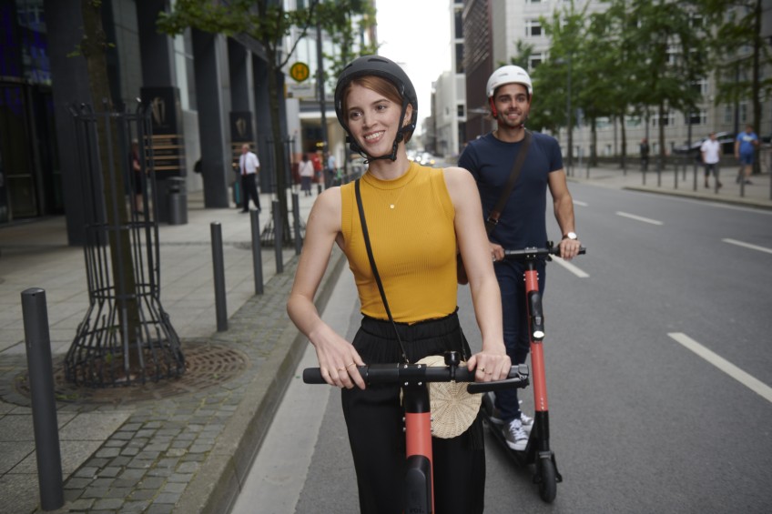 Pressemitteilung E-Scooter - Mann und Frau fahren E-Scooter in der Stadt
