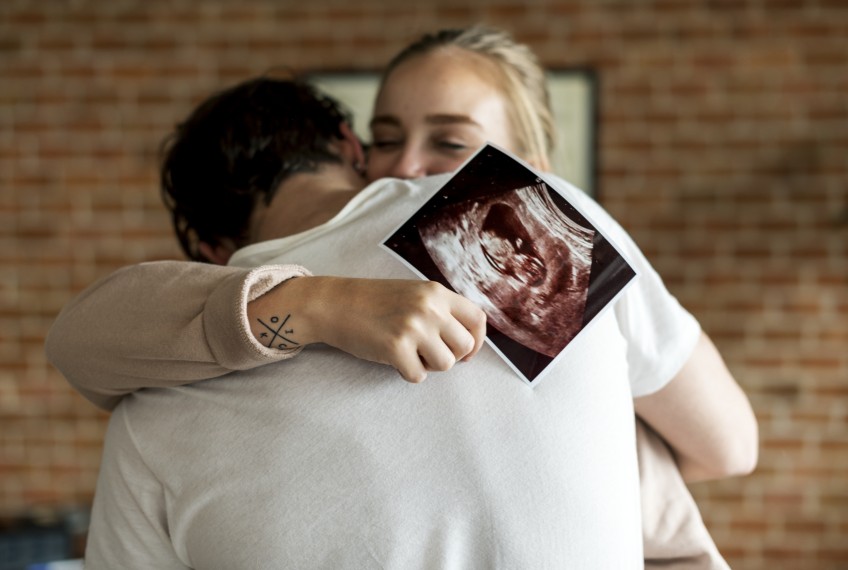 Pressemitteilung Familienumfrage - Frau mit Ultraschallbild in der Hand umarmt Mann