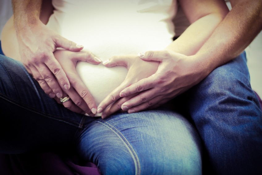 Pressemitteilung Familienumfrage - Frau und Mann formane Herz aus Hand vor Babybauch