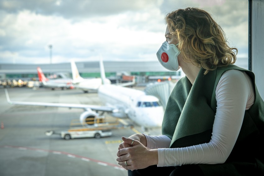 Pressemitteilung Umfrage Konjunkturpaket - Frau mit Maske am Flughafen