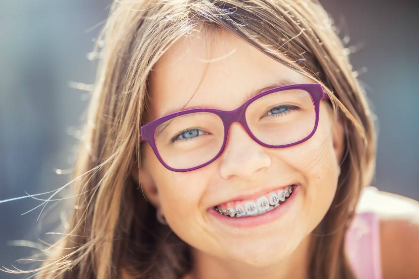 Pressemitteilung Zahnpangen für Kinder: Mädchen mit Brille und Zahnspange